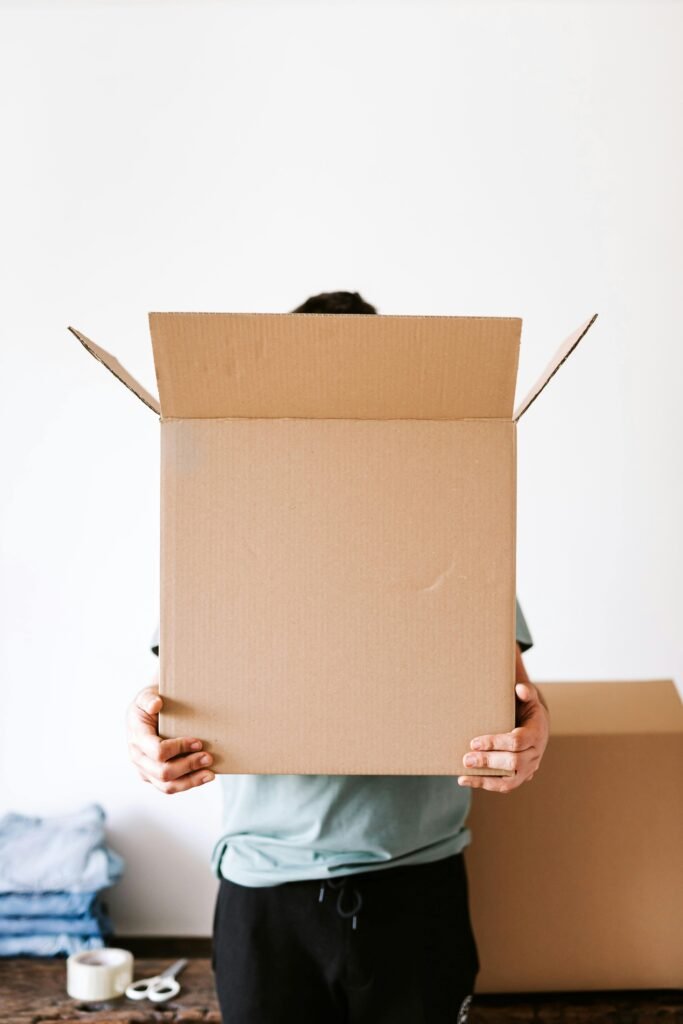 Unrecognizable man with carton box in apartment