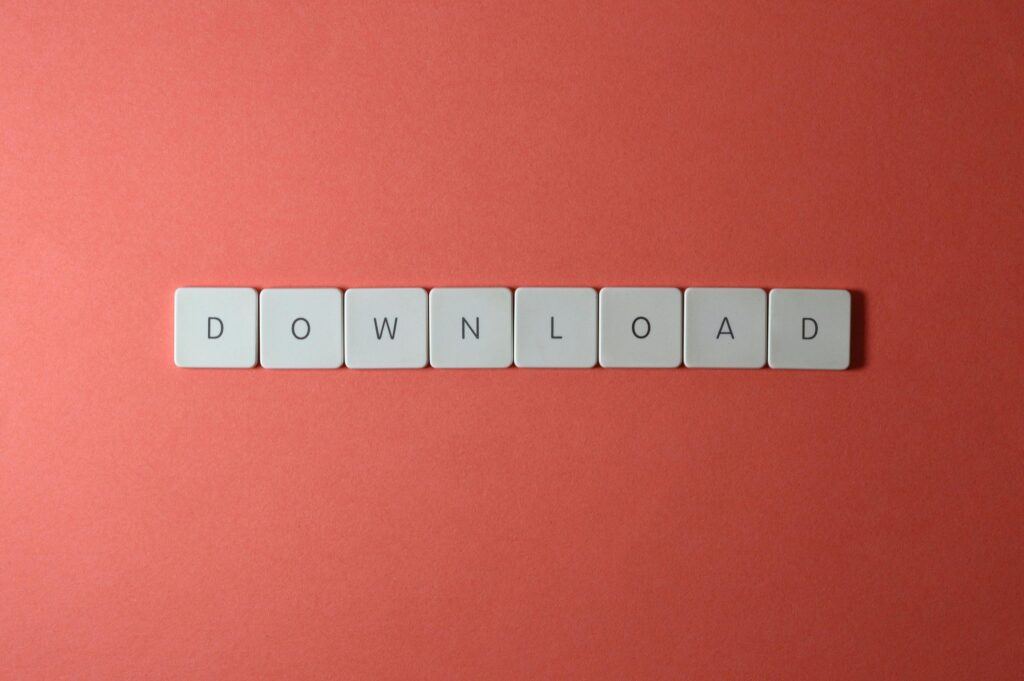 Minimalist photo of keyboard tiles spelling 'DOWNLOAD' on a red background.